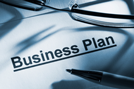 Business Plan typed on paper with classes and pen on top