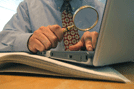 Man Using Magnifying Lense to examine financials